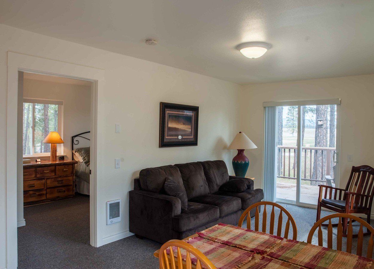 A living room with a couch , table , chairs and sliding glass doors leading to a deck.