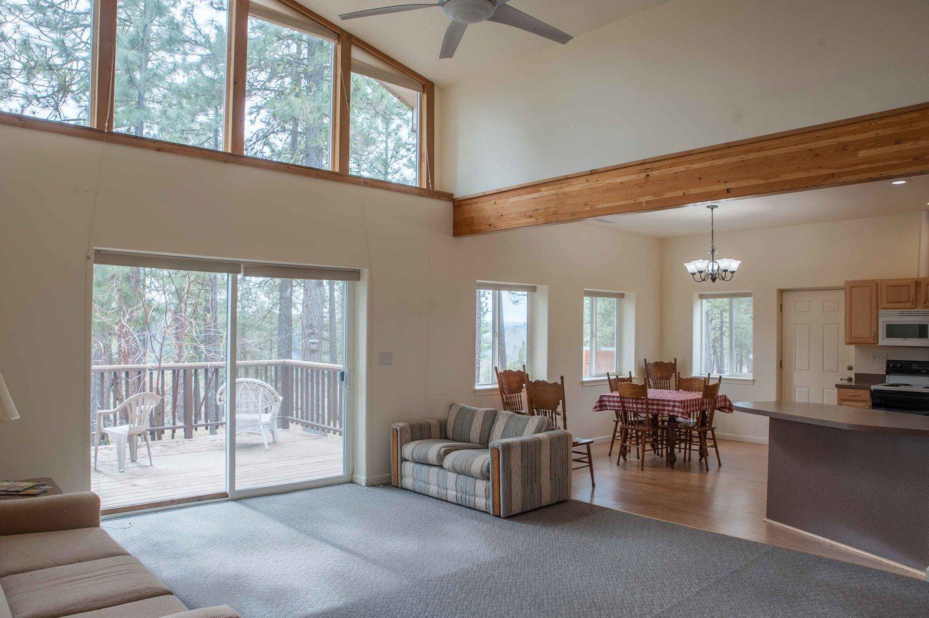 A living room with a couch , table , chairs and a ceiling fan.