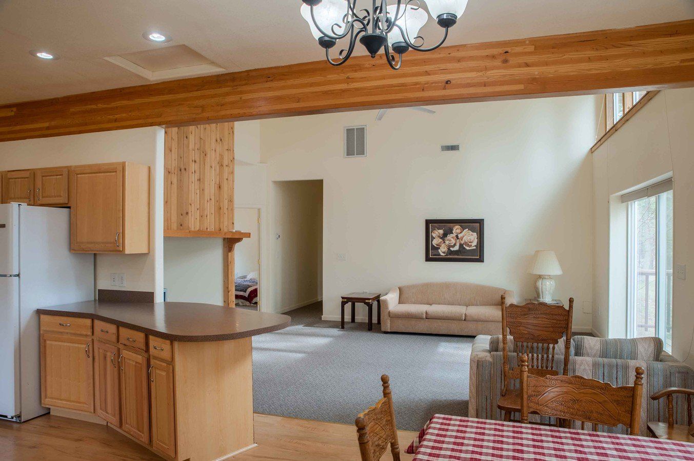 A living room with a couch , table , chairs and a refrigerator.