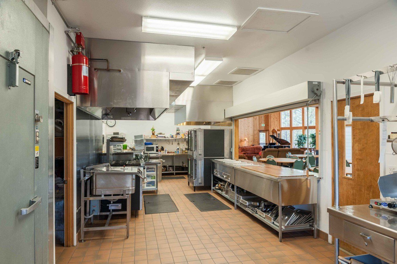A large kitchen with stainless steel appliances and a fire extinguisher on the wall.