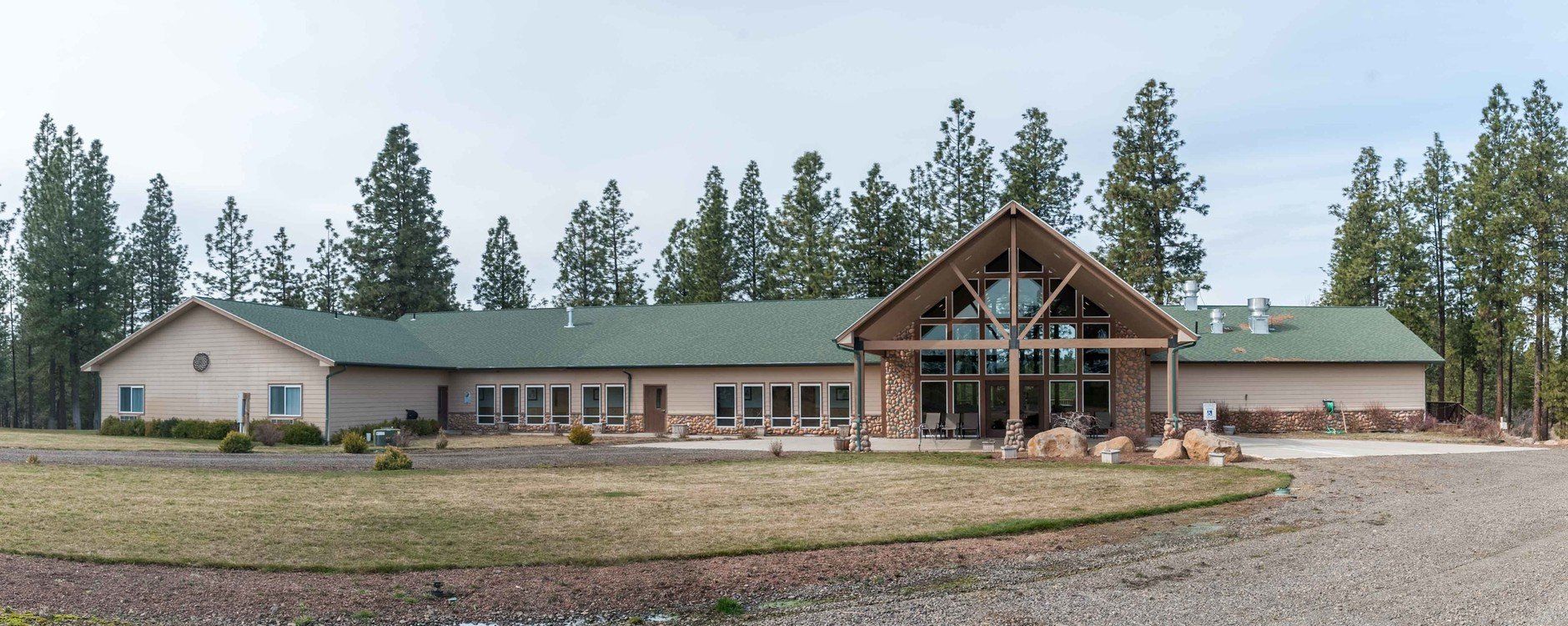 A large house with a green roof is surrounded by trees