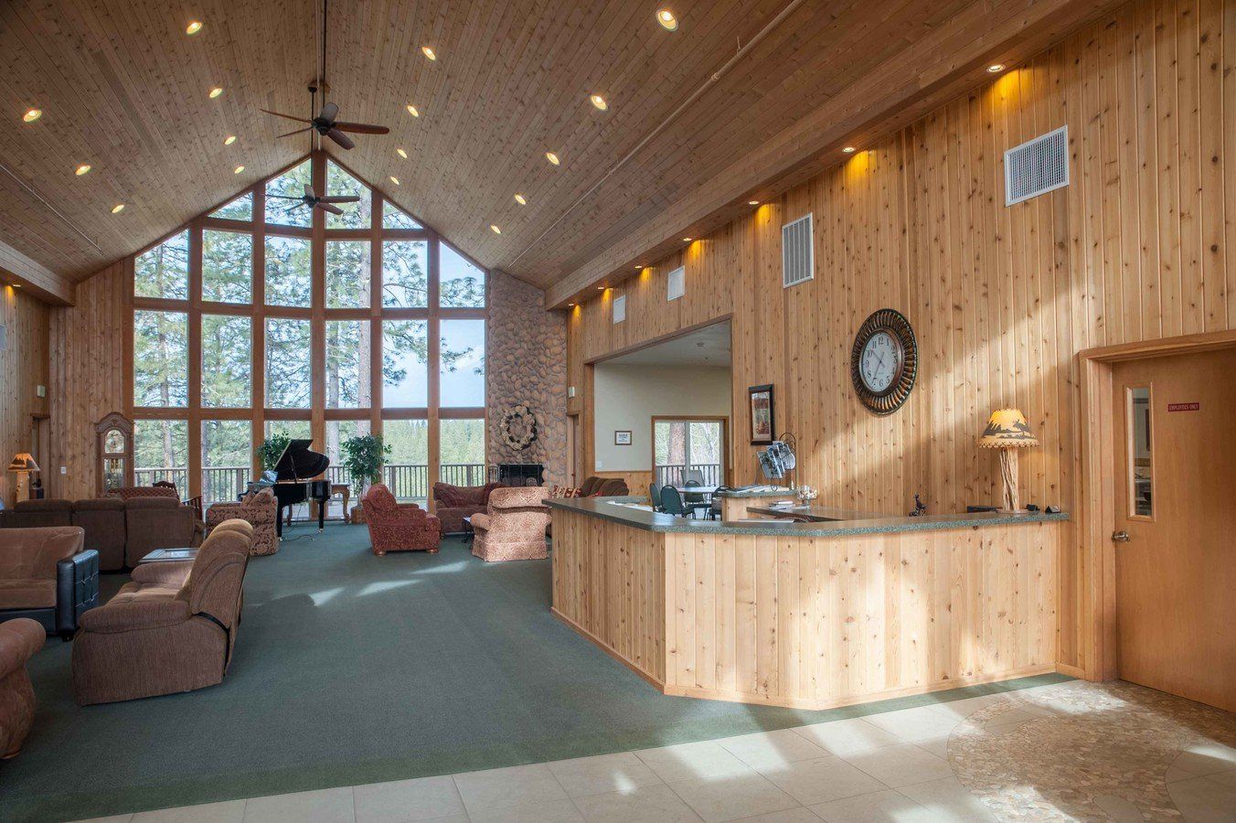 A large wooden lobby with a piano and a clock on the wall.
