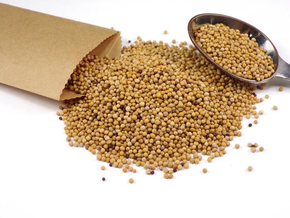 A bag of mustard seeds next to a spoon