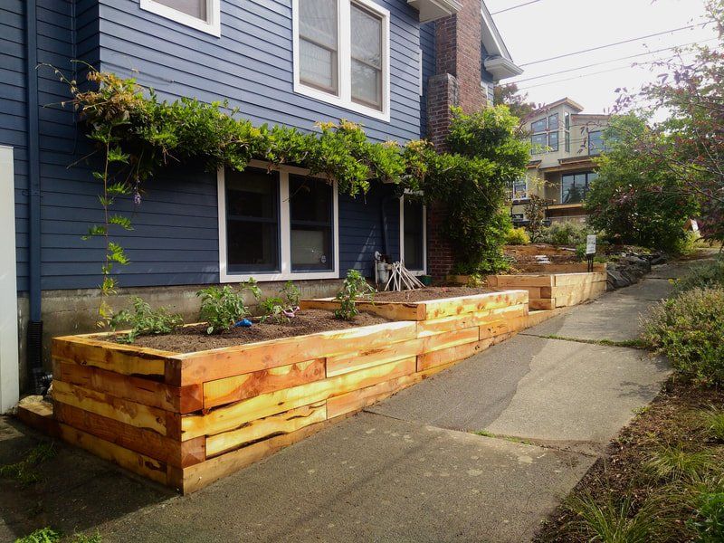 A blue house with a wooden planter in front of it.