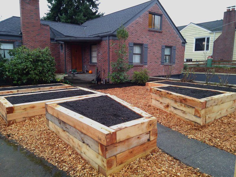 A brick house with wooden raised beds in front of it