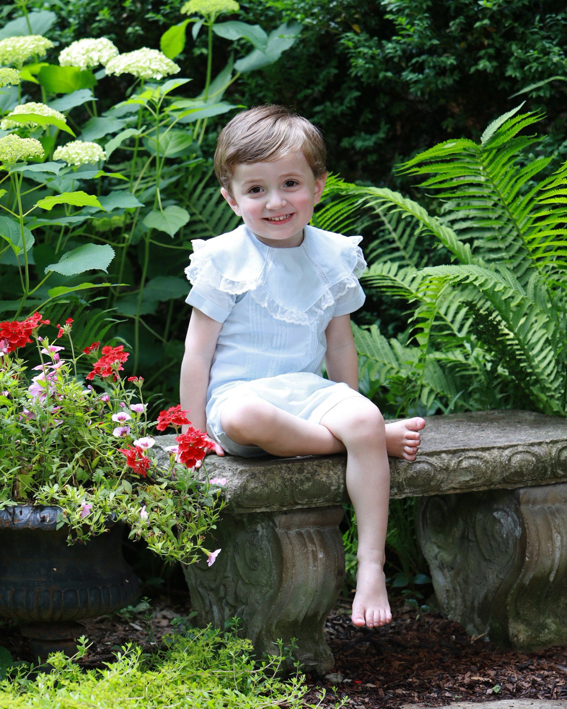 Boy sitting in garden with blooming flowers