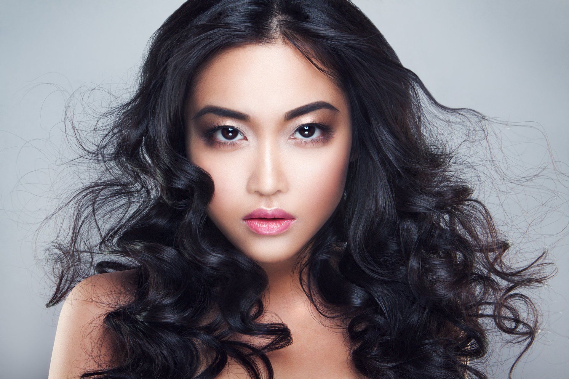 A woman with long curly hair is looking at the camera.
