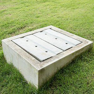 Concrete utility cover set in a grassy lawn.