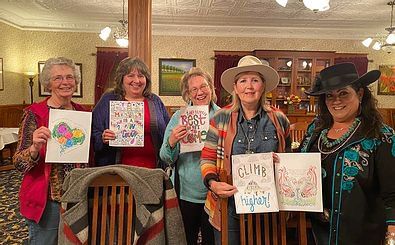 A group of women are standing next to each other in a room holding signs.