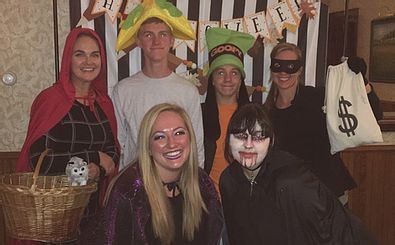 A group of people dressed in halloween costumes are posing for a picture.