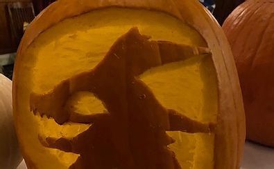 A pumpkin with a silhouette of a witch carved into it.