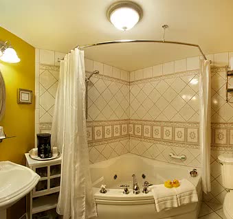 A bathroom with a tub , sink , toilet and mirror