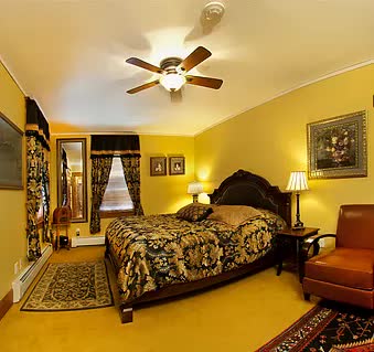 A bedroom with a large bed and a ceiling fan