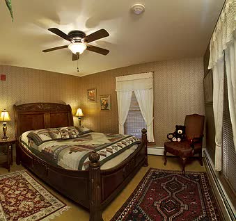 A bedroom with a bed , chair , rug and ceiling fan