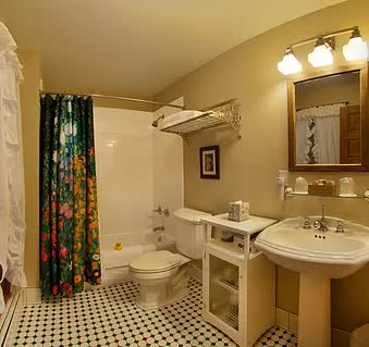 A bathroom with a sink , toilet , shower and mirror.