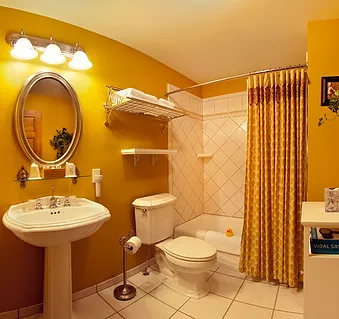 A bathroom with yellow walls a sink toilet and shower