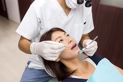 A woman is getting her teeth examined by a dentist.