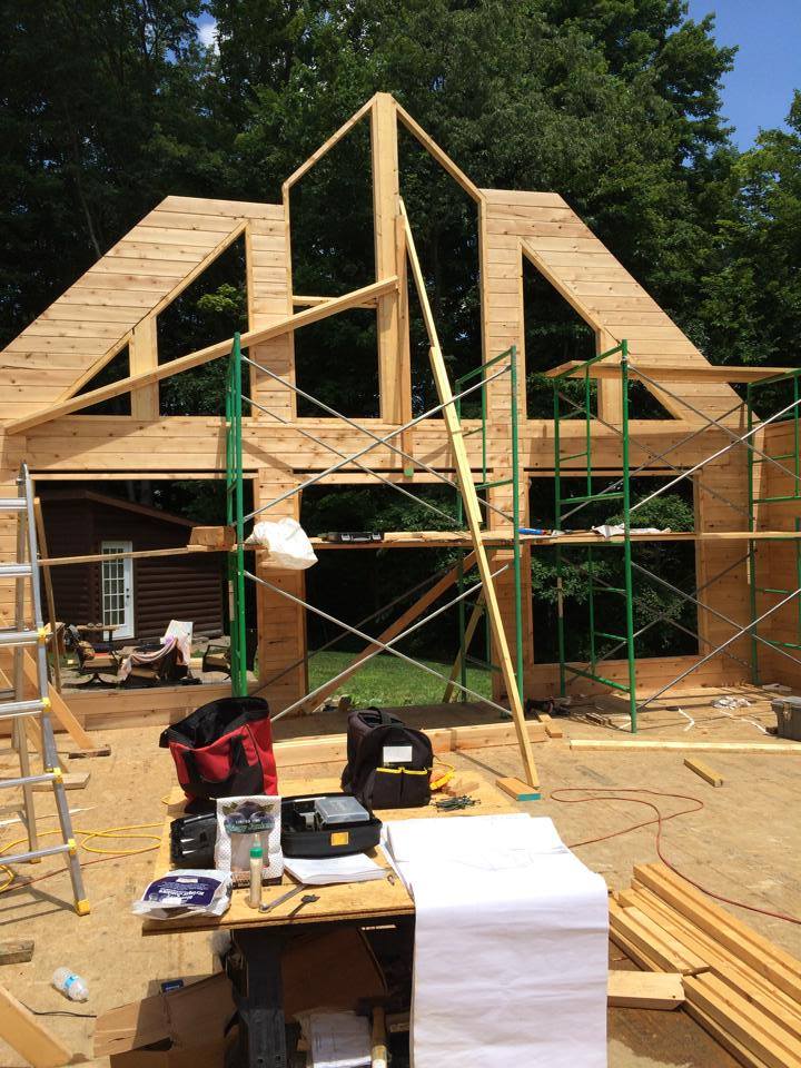 Wooden house frame under construction with scaffolding and tools in front