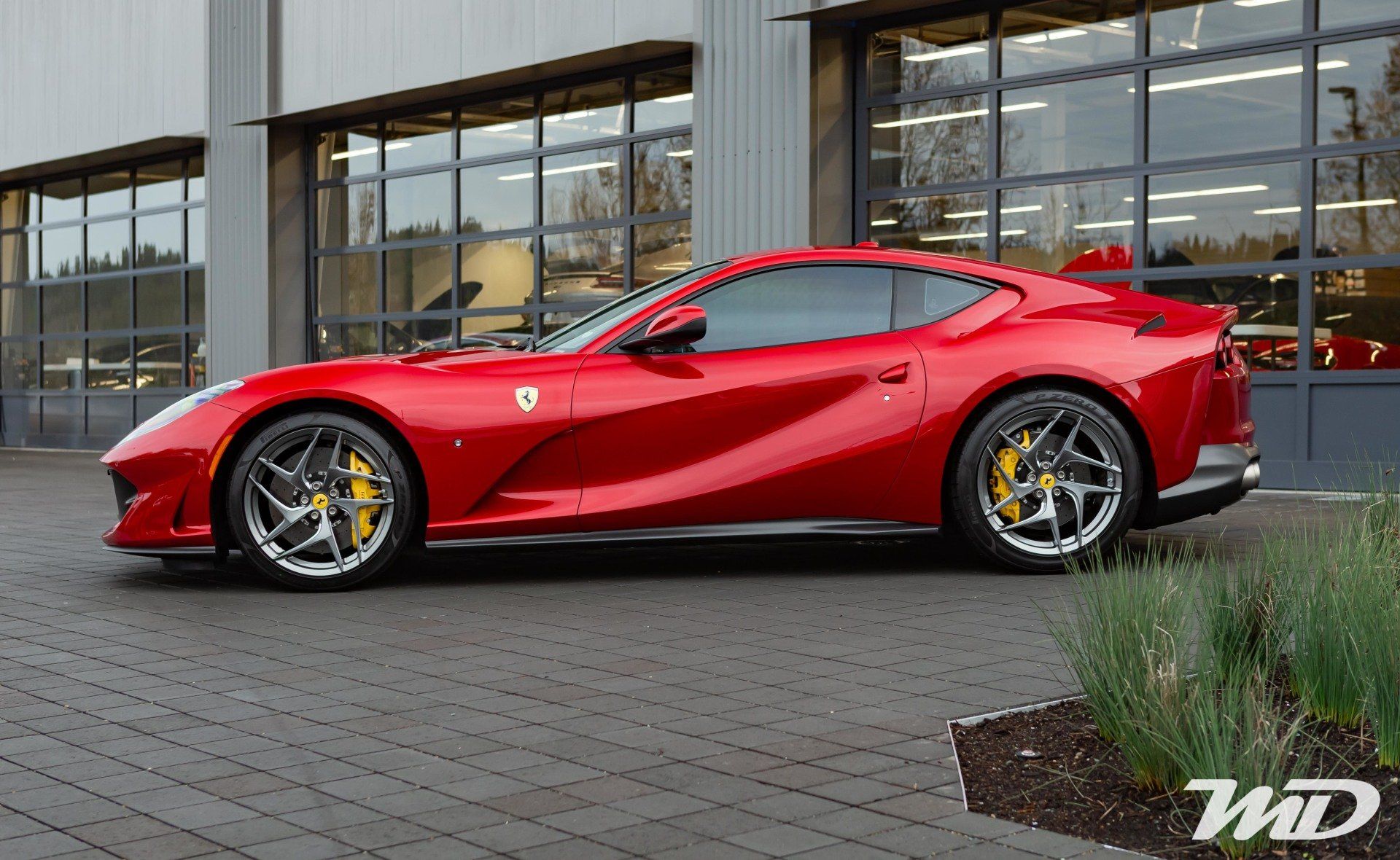 A red ferrari is parked in front of a building.