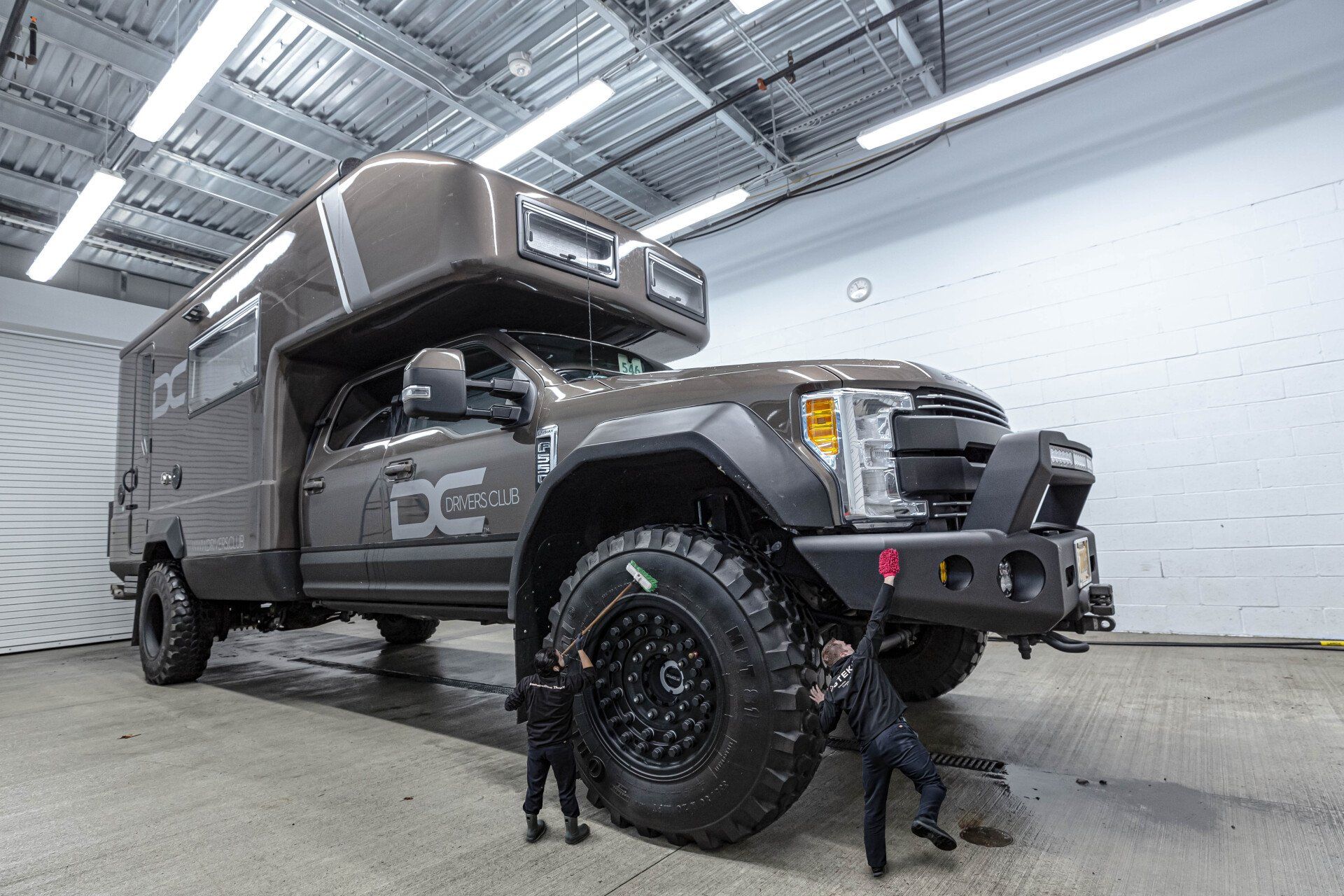 A truck with a camper on top of it is parked in a garage.