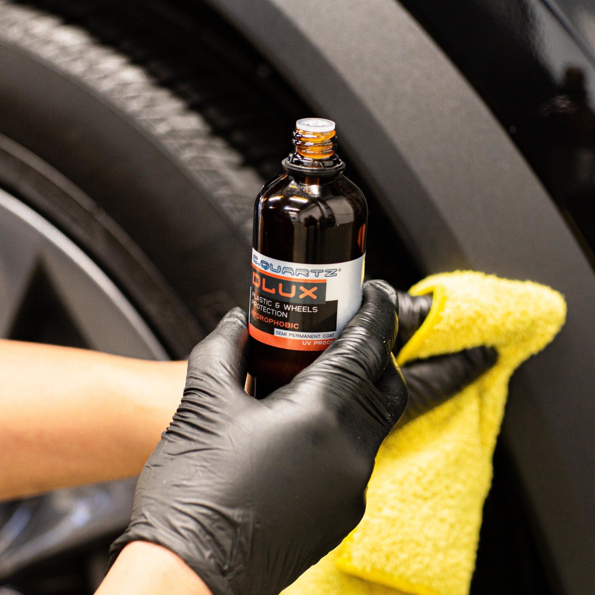 A person wearing black gloves is holding a bottle of flux