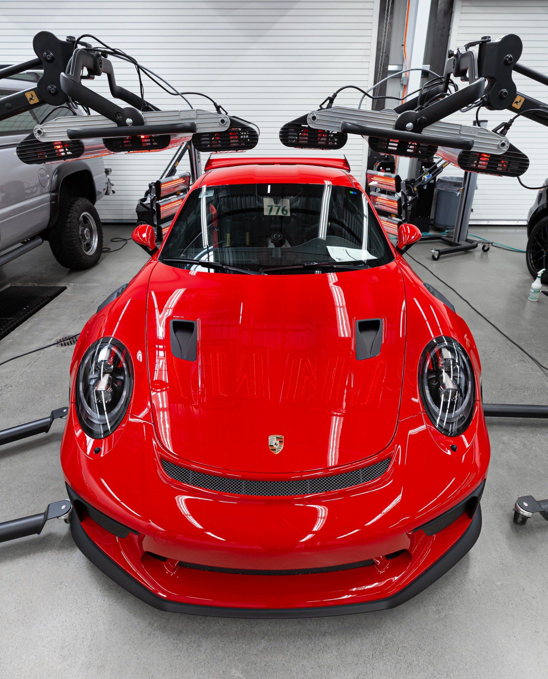 A red porsche is sitting in a garage surrounded by cameras.