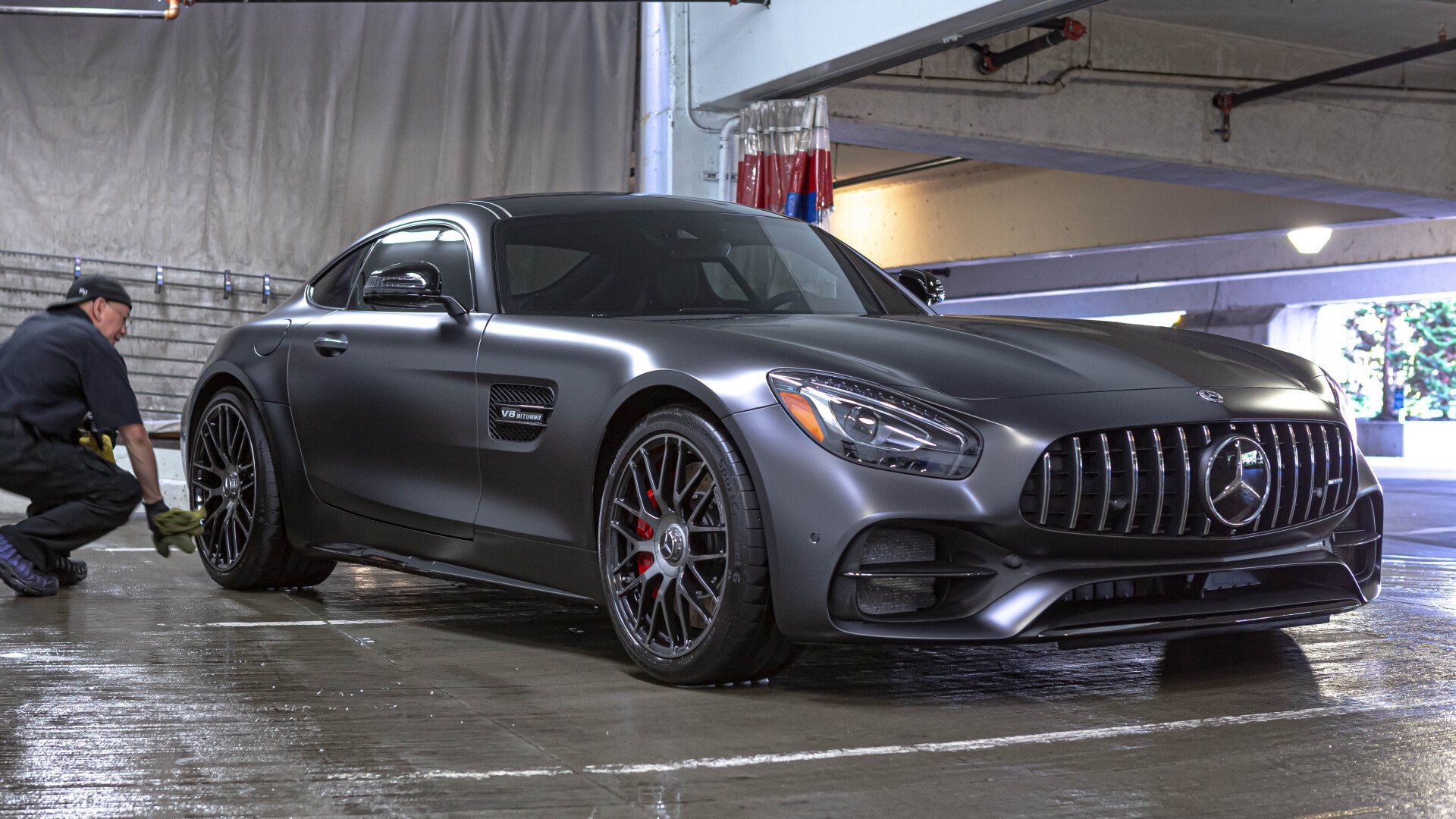 A man is washing a mercedes amg gt in a parking garage.