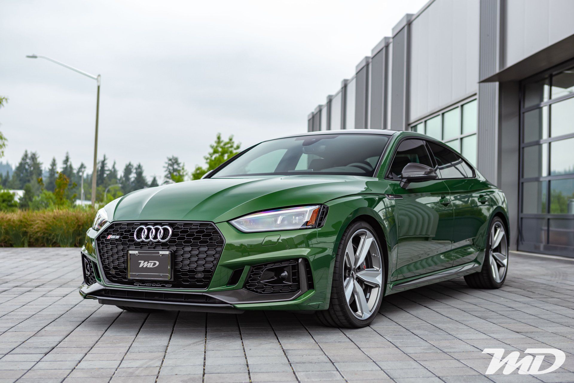 A green audi rs 5 is parked in front of a building.