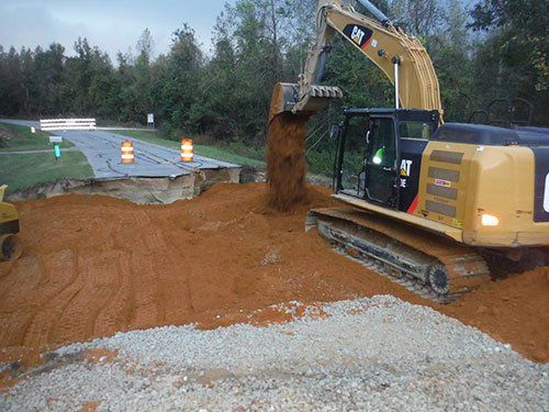 a bulldozer is digging a hole in the ground near a road .