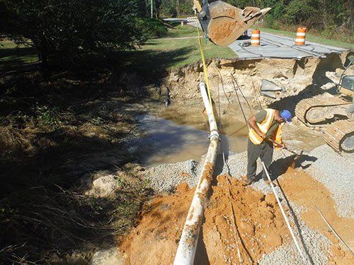 a man is standing in the dirt next to a pipe .
