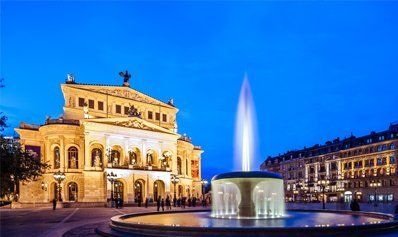 Ein Brunnen vor einem großen Gebäude bei Nacht.