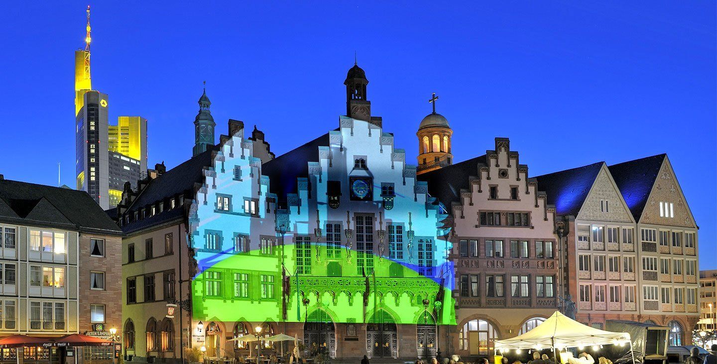 In einer Stadt ist nachts eine Reihe von Gebäuden beleuchtet.