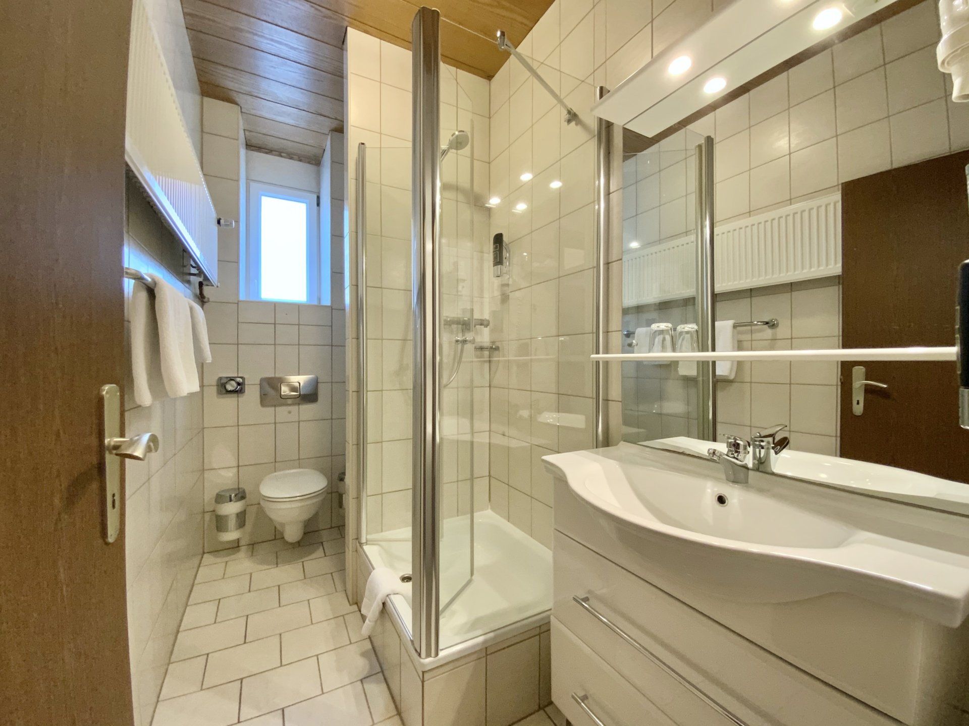 A bathroom with a sink , toilet , shower and mirror.