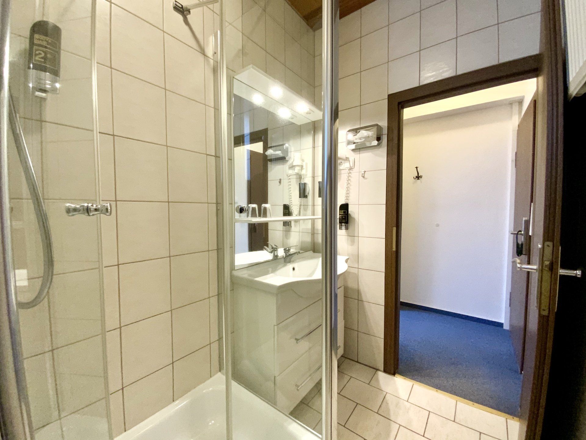 A bathroom with a shower , sink and mirror.