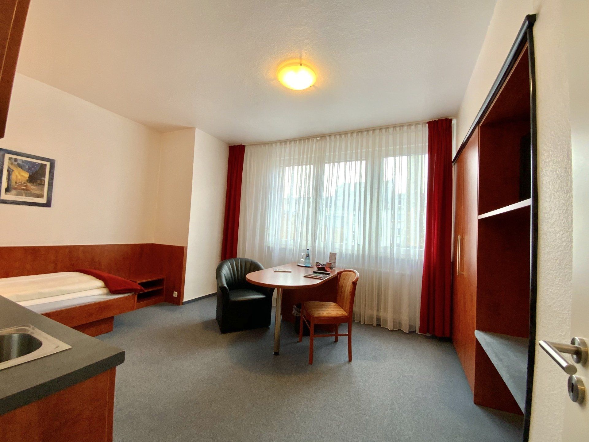A hotel room with a table and chairs and a bed