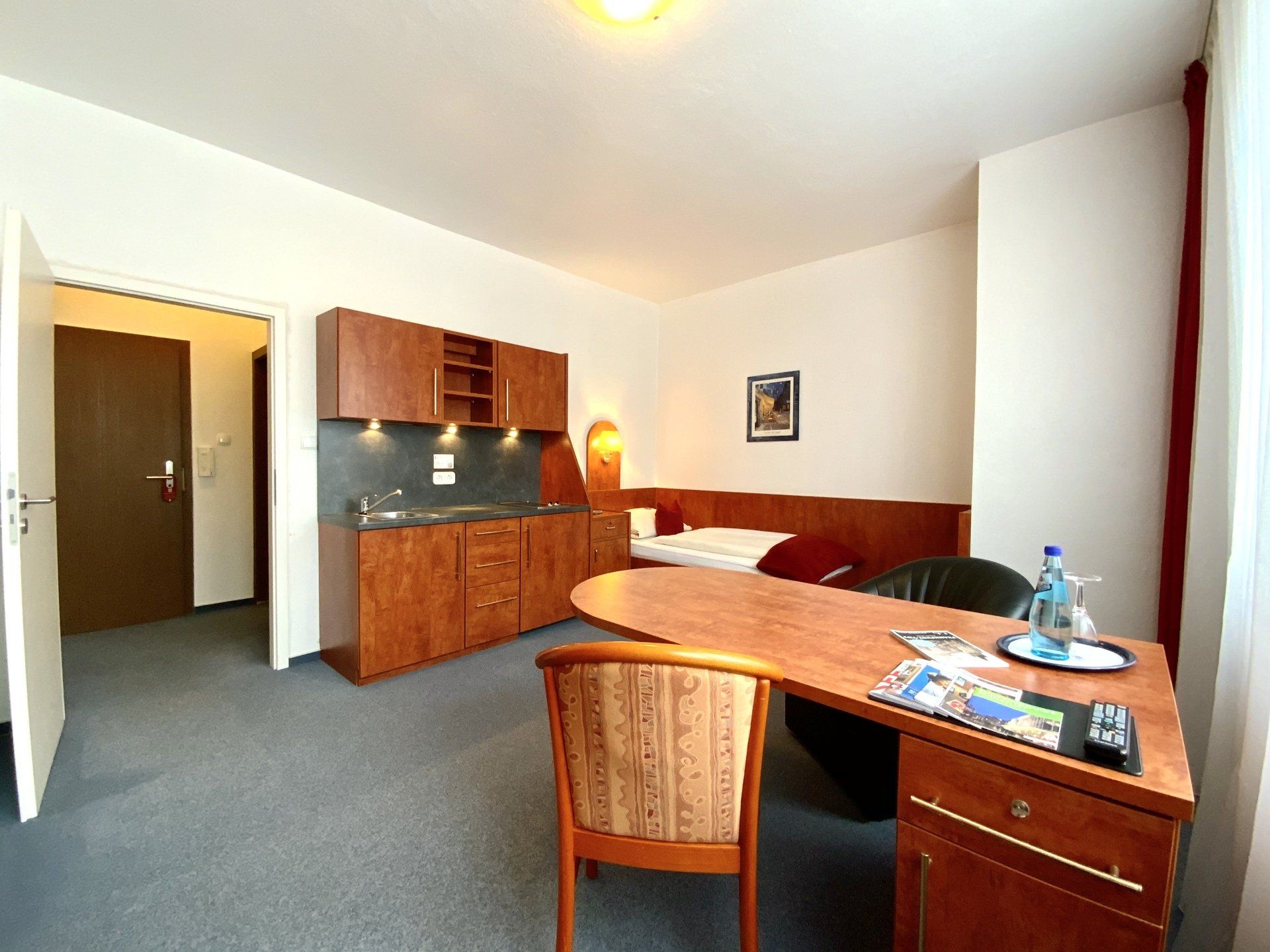 A hotel room with a desk a chair and a bed