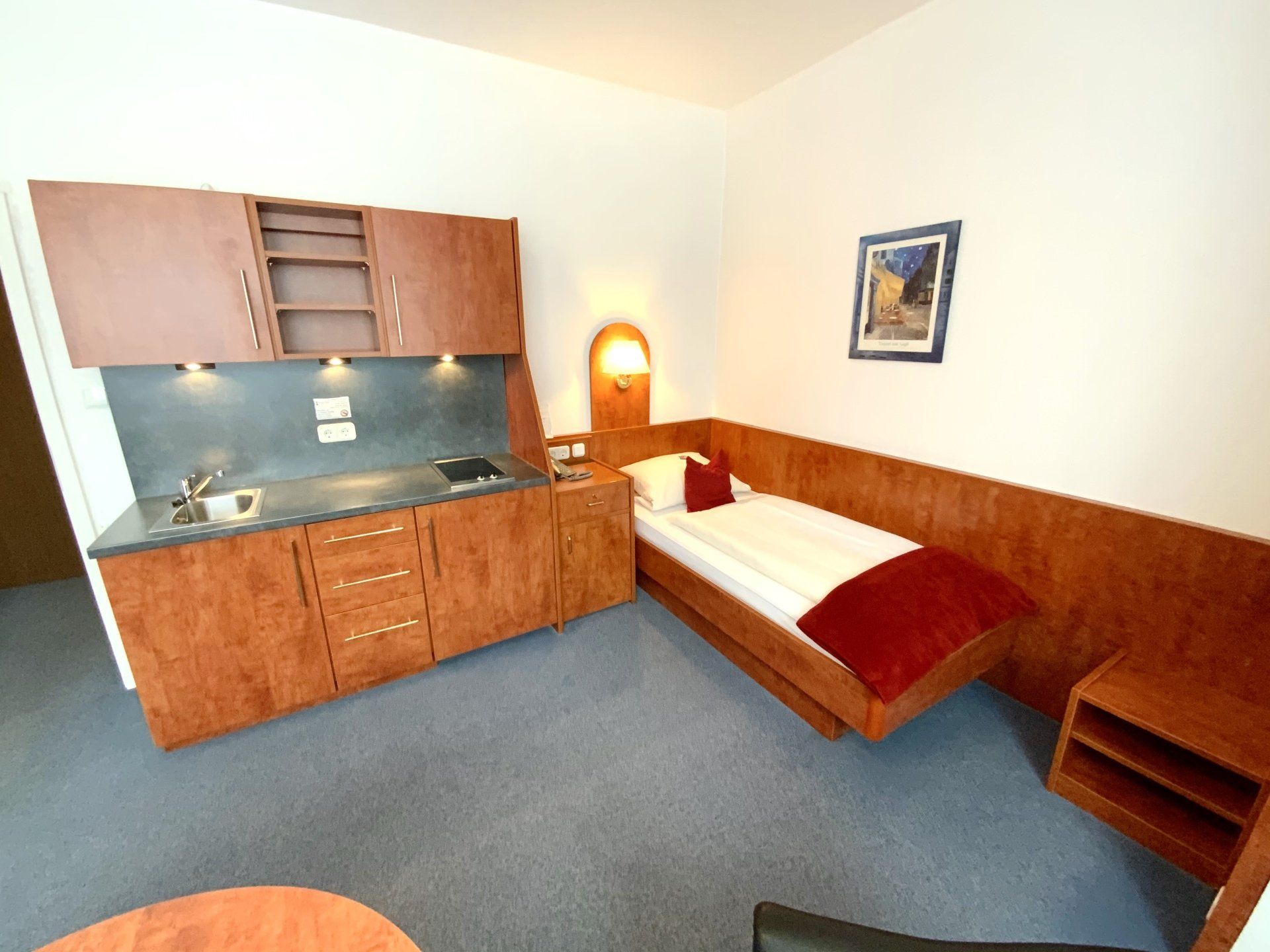 A hotel room with a single bed and a kitchen