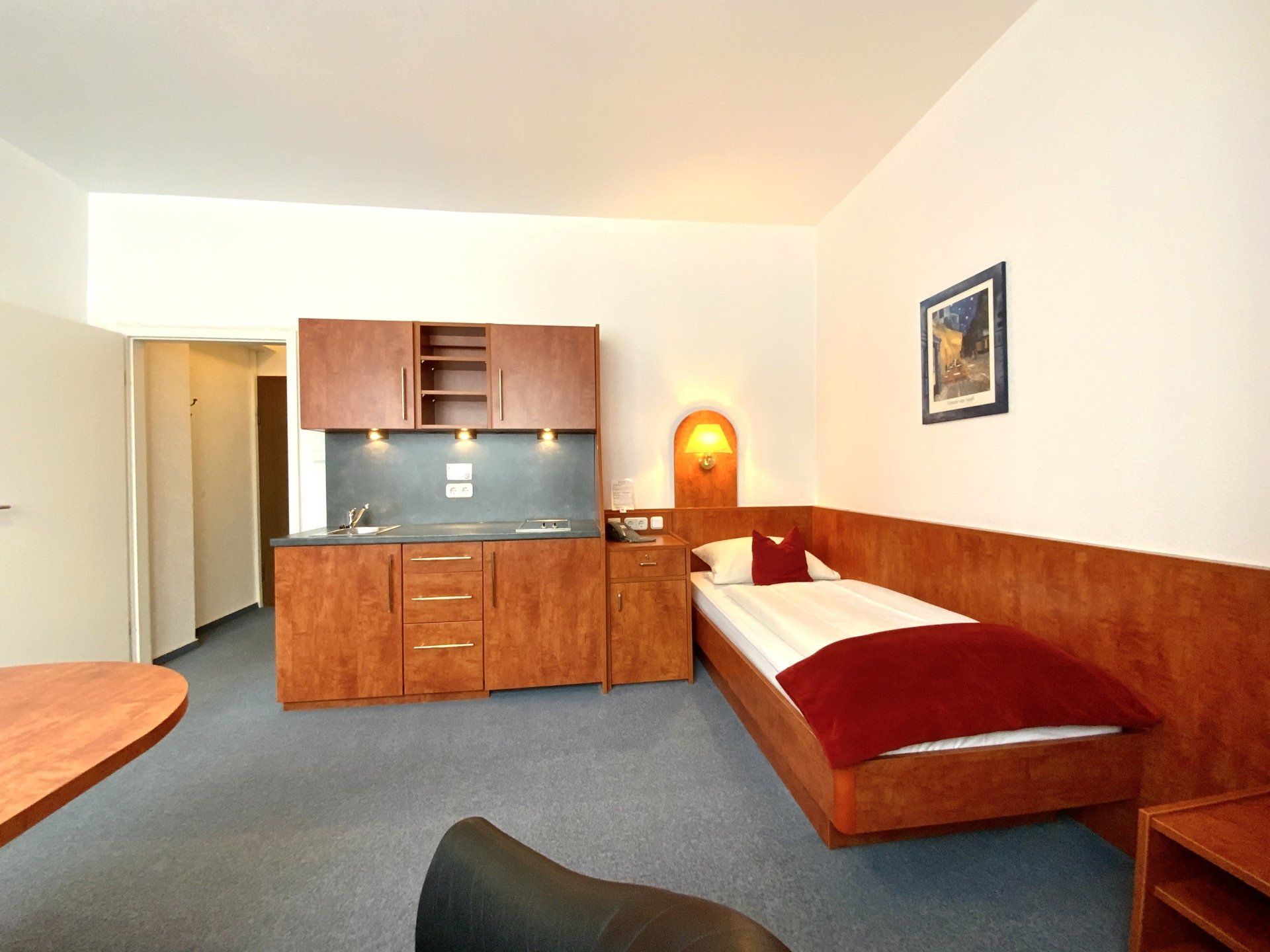 A hotel room with a single bed and a kitchen