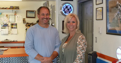 Two smiling people standing indoors in a bright office or waiting room