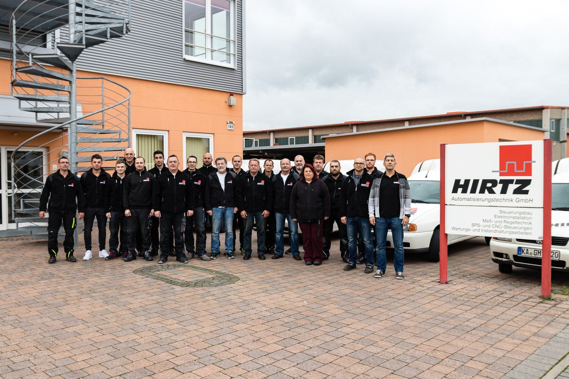 Eine Gruppe von Menschen posiert vor einem Gebäude für ein Foto.