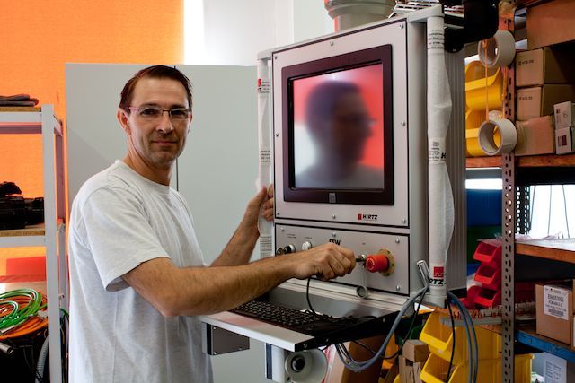 Ein Mann im weißen Hemd steht vor einem Computermonitor.