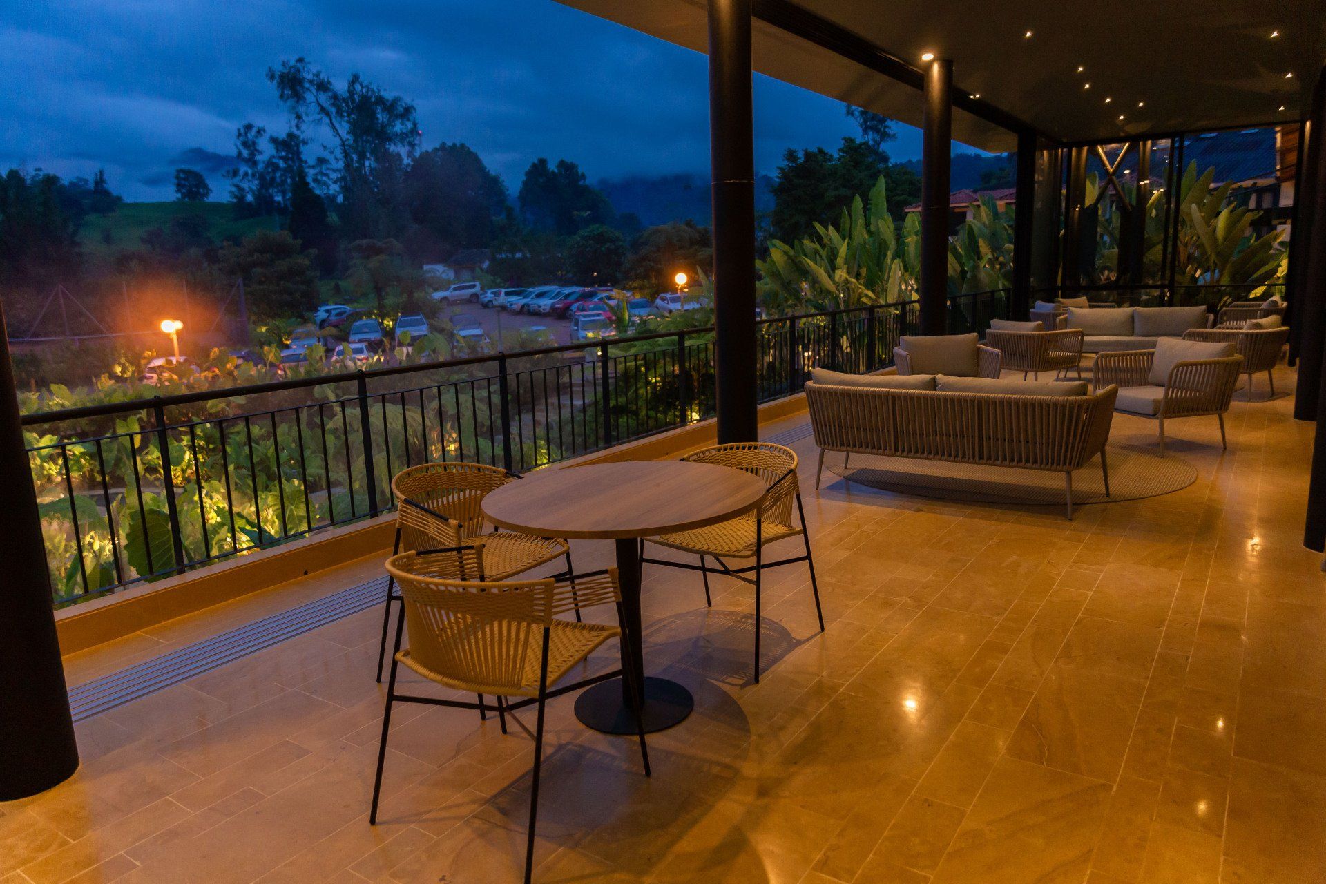 Barra 85 terrace at Termales El Otoño, featuring tables, chairs, and a nighttime view of gardens and outdoor areas.