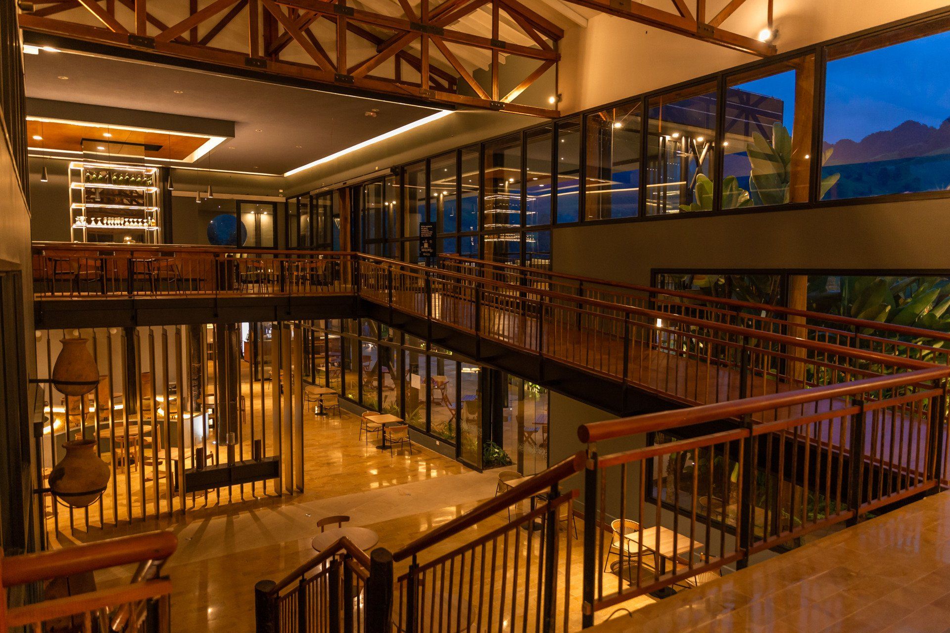 Bar interior at Termales El Otoño, featuring walkways, railings, warm lighting, and multi-level dining spaces.