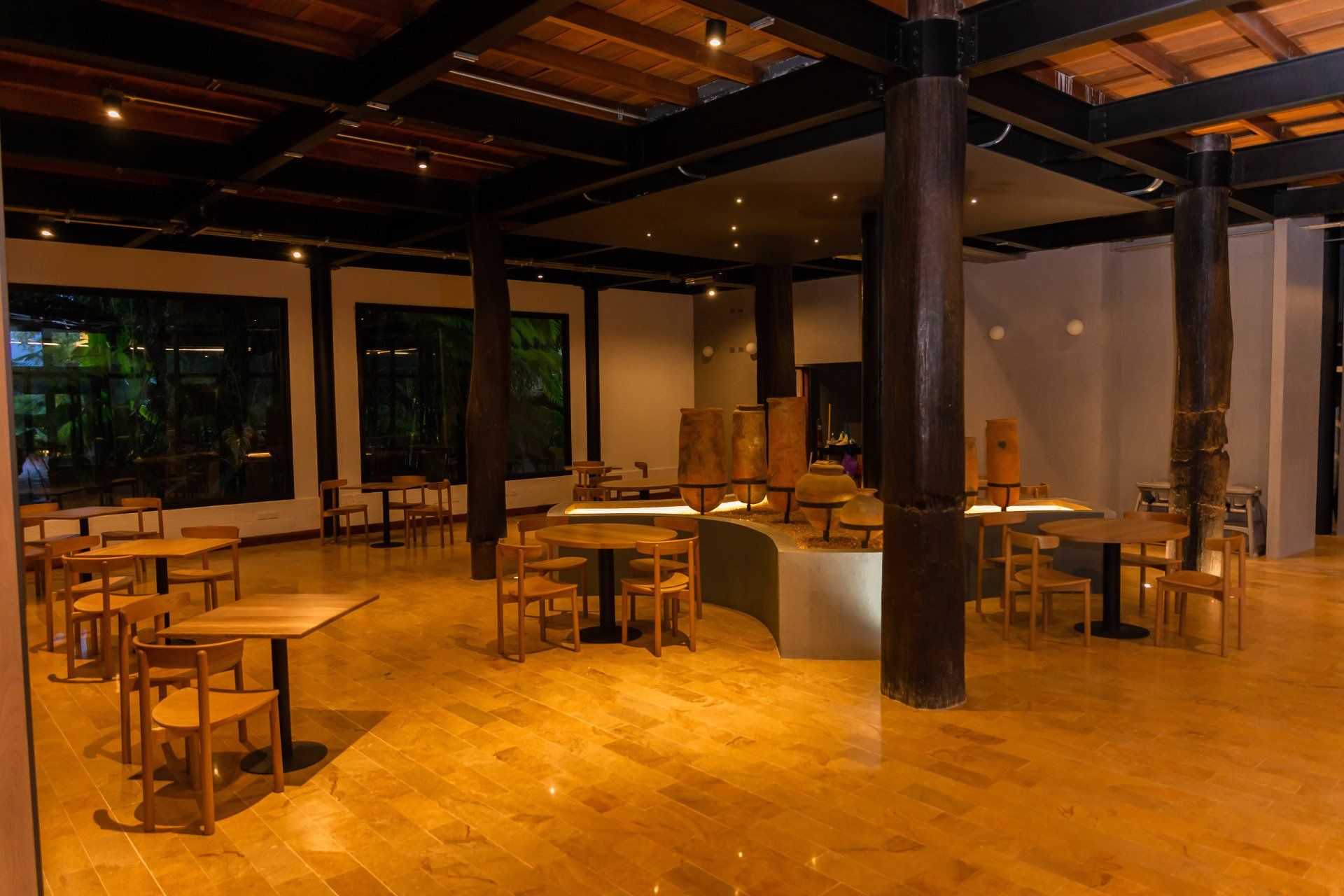 Restaurant Origen interior at Termales El Otoño, with wooden tables, dark columns, and a warm atmosphere in Manizales.