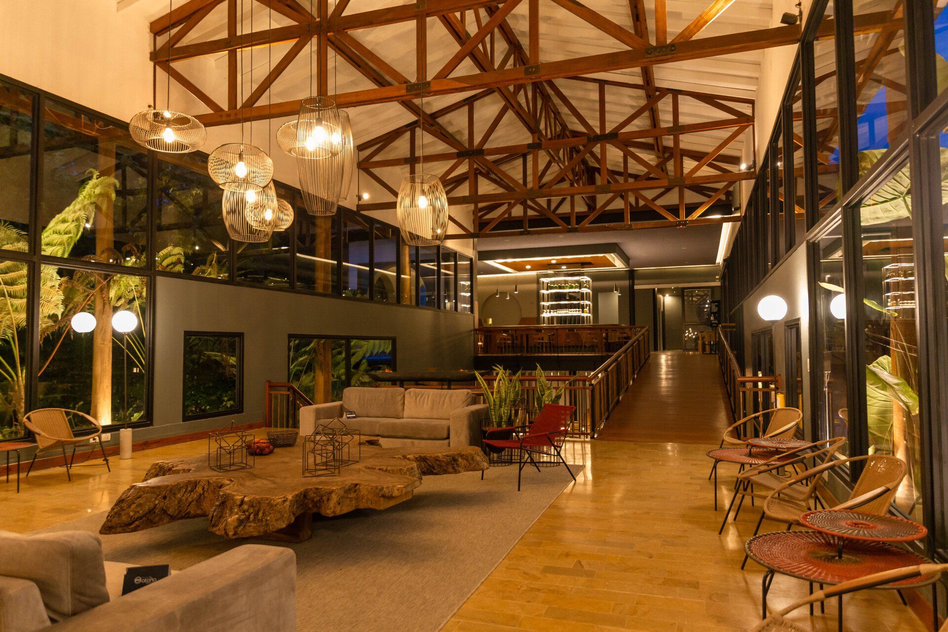 Reception area at Termales El Otoño, featuring an indoor lounge, hanging lamps, a high wooden ceiling, and a warm atmosphere.