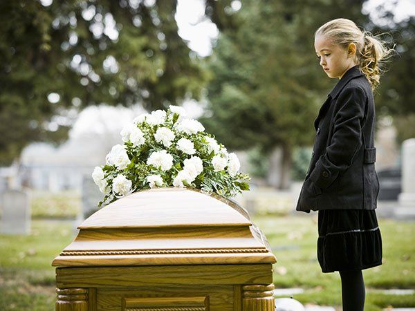 Girl Looking in Coffin at Cemetery — Law Firm in Modesto, CA Girl Looking in Coffin at Cemetery — Law Firm in Modesto, CA