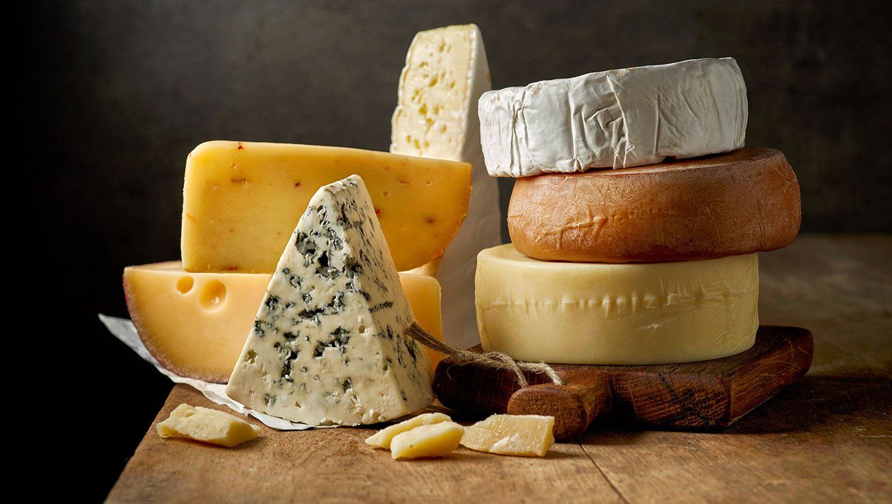 A variety of stacked cheeses A variety of stacked cheeses on a wooden table.