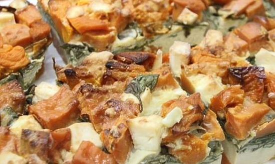 a close up of a food with vegetables and cheese.