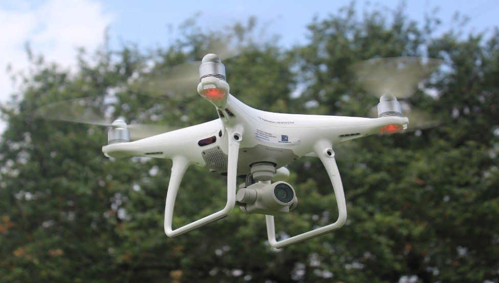 A drone is flying in the sky with trees in the background - Baton Rouge, LA - Coastal Environments, Inc.