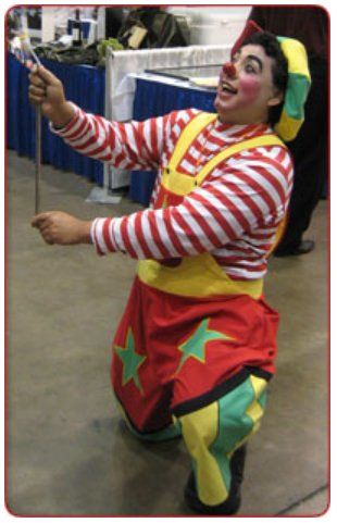 A clown is kneeling down and holding a cane